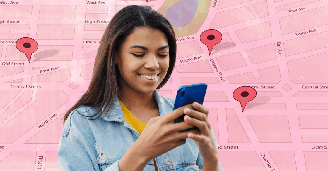 A young woman looks at her phone against a map with red pins specifying various points of interest.