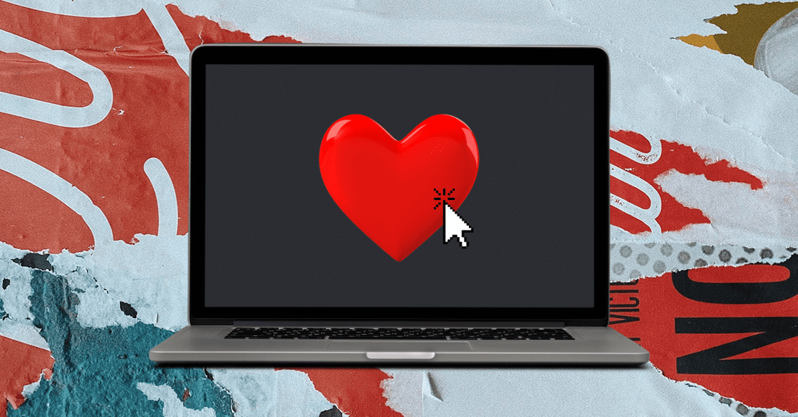 A laptop with a red heart on the screen and a white arrow cursor.