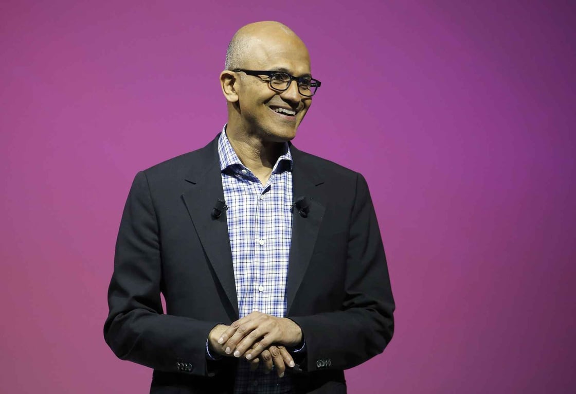 Microsoft CEO Satya Nadella speaks on stage against a purple backdrop.