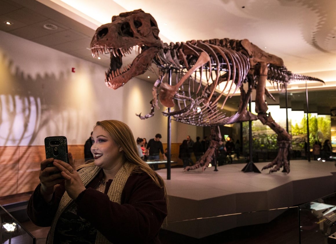 woman taking a selfie with a dino fossil