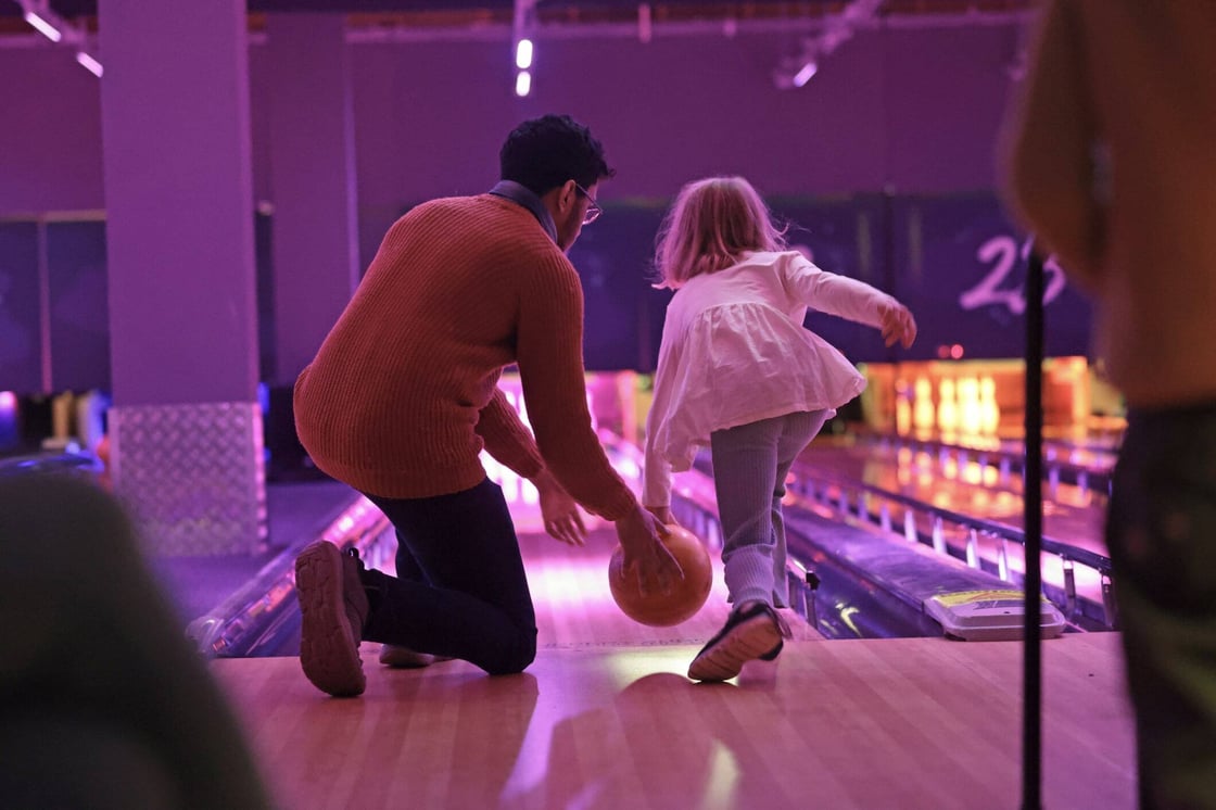 A man and a young girl bowling.